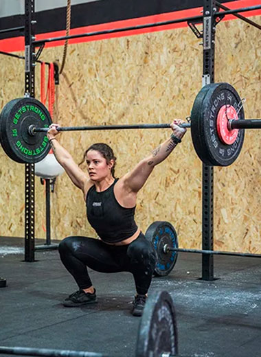 Imagen de mujer levantando pesas en el gimnasio tomando una clase de Halterofilia